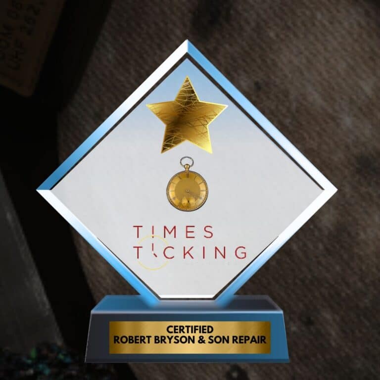 Diamond-shaped glass award with a gold star, a small antique gold-dial pocket watch, and the Times Ticking logo, mounted on a blue base with a gold plaque reading "Certified Robert Bryson & Son Repair."